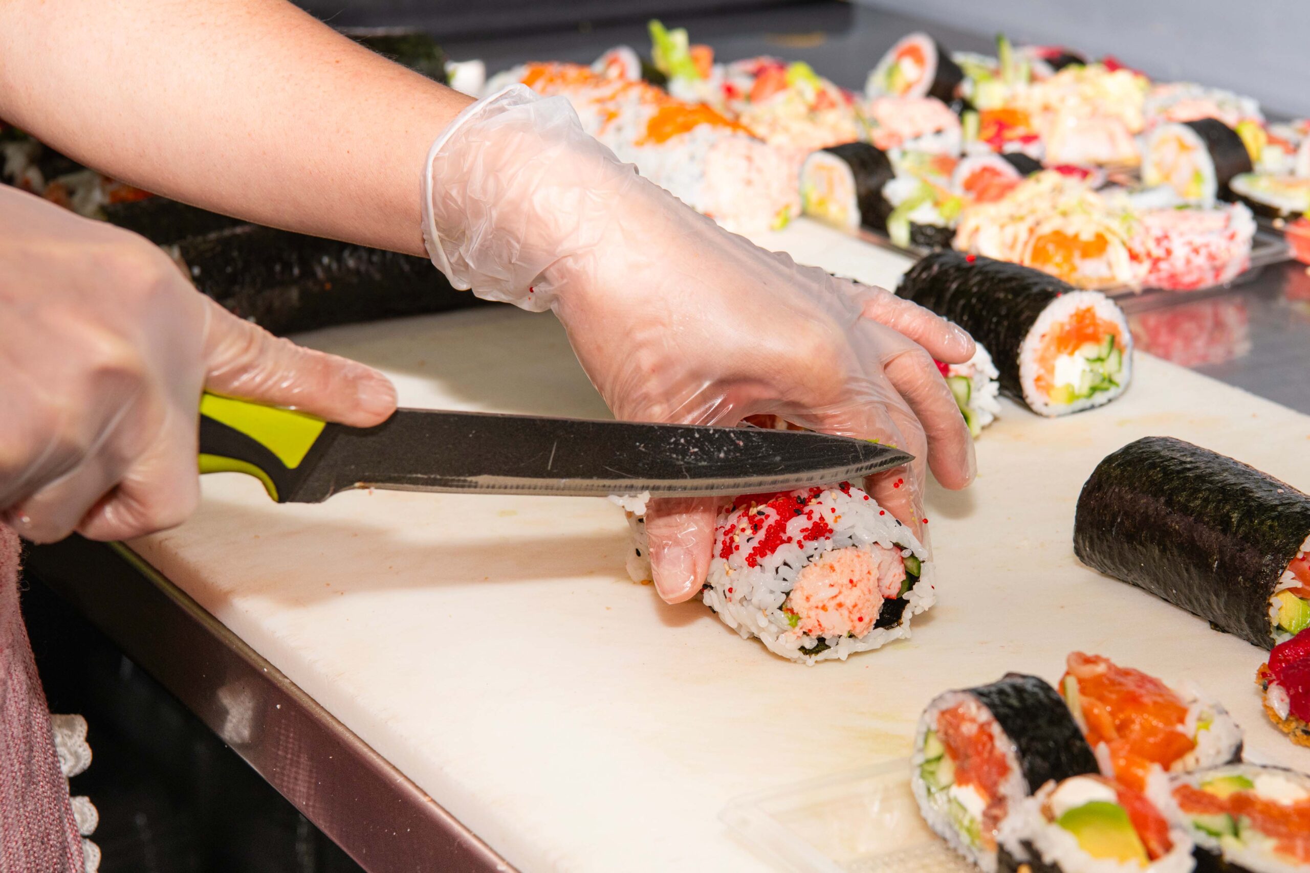 Chef de Sushi Oshima coupant un maki frais sur une planche