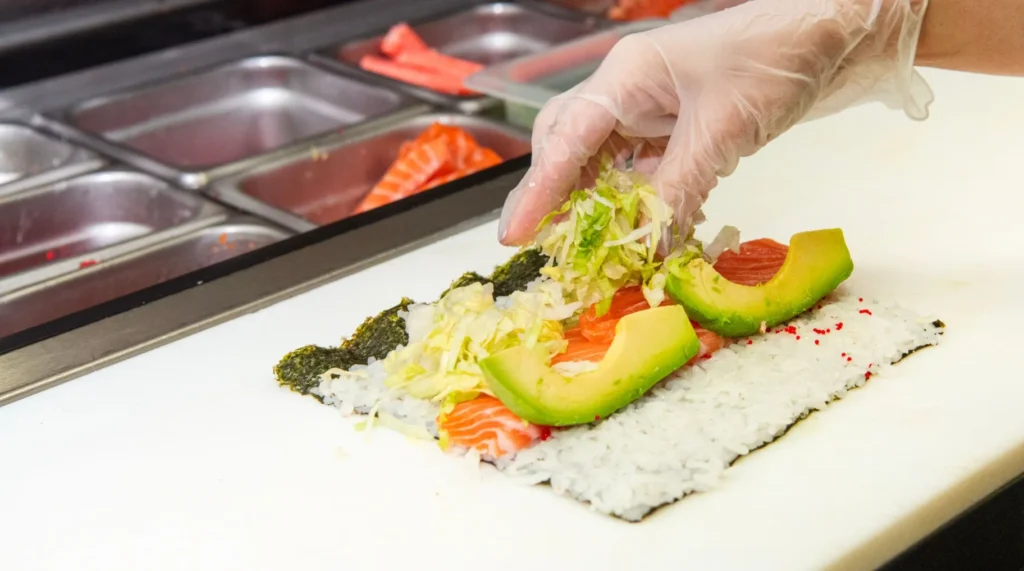Préparation d’un maki à l’avocat sur une feuille de nori